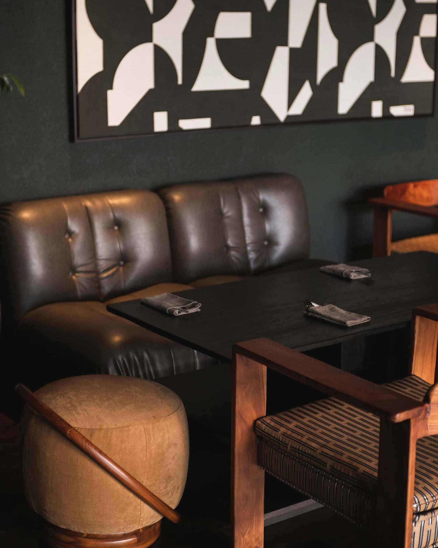 Interior of a cafe with dark leather seating, abstract wall art, and wooden furniture.